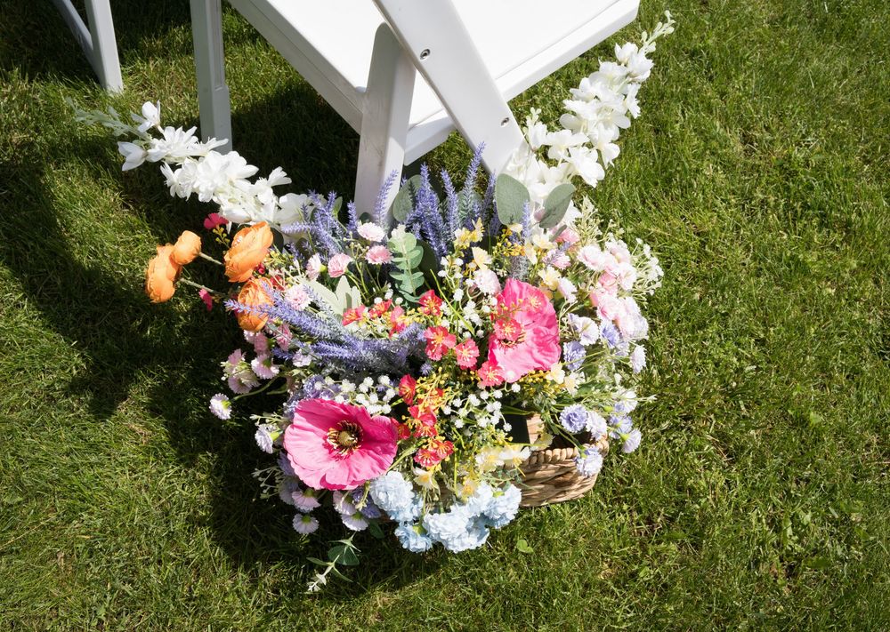Floral decorations and wreaths with colorful spring flowers arranged on green grass in an outdoor setting.