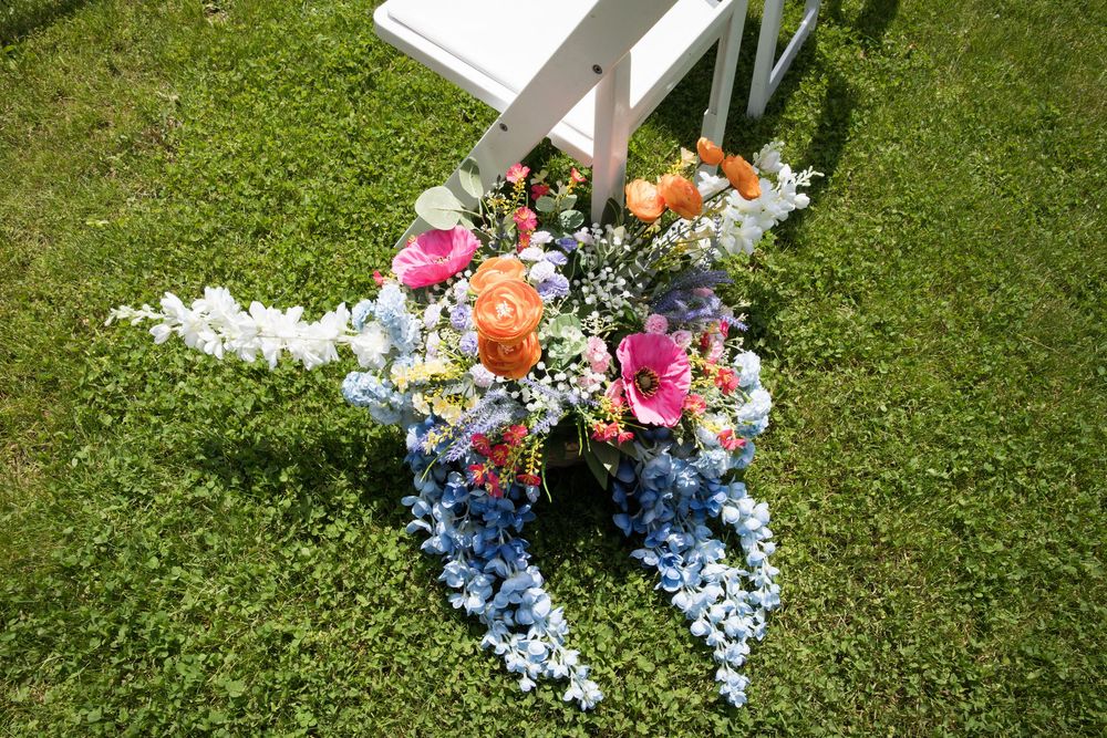 A row of colorful artificial flowers creatively arranged along a grassy ground in a decorative outdoor display pattern.