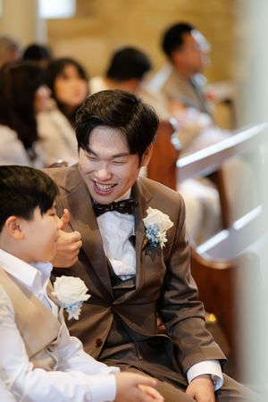 Wedding guests in brown suits share joyful moments during ceremony.