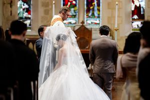A bride and groom share a romantic moment inside an elegantly decorated church venue with stained glass windows.