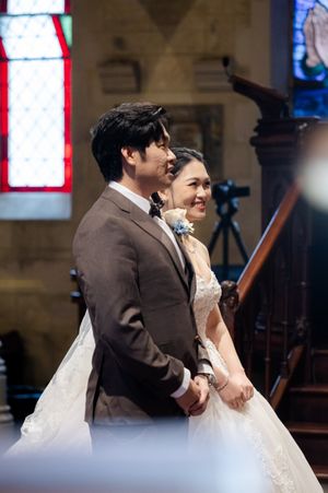 Inside a church with stained glass windows during a wedding ceremony.