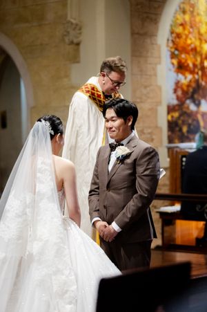 A wedding ceremony in progress with autumn colors visible through arched windows.
