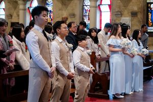 Wedding ceremony attendees stand in formal attire inside a traditional church sanctuary.