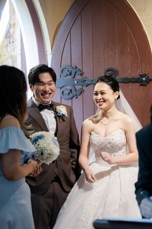A joyful couple celebrates at their wedding ceremony outside a wooden church door with ornate hinges.