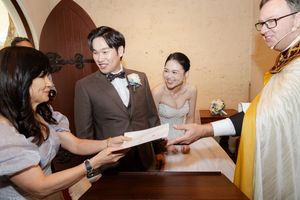 Wedding ceremony participants signing official documents at a ceremonial table.