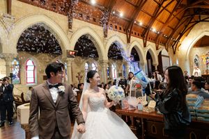A wedding ceremony takes place in a beautiful historic church with vaulted wooden ceilings and ornate decorations.