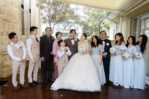 Wedding party poses along stone wall in romantic outdoor setting with bridesmaids in light blue dresses.