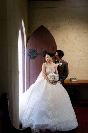 Romantic wedding photo session in a rustic room with natural light streaming through arched windows.