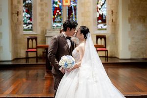 Church wedding ceremony with bride in white gown and stained glass windows.