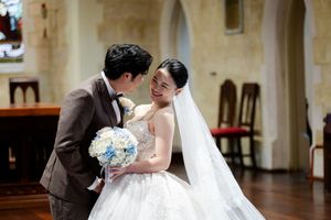 Bride in a flowing white wedding dress exchanging vows with groom during church ceremony.