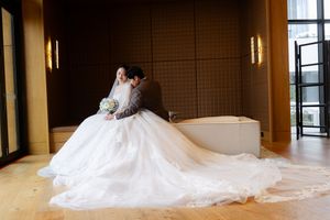 Wedding couple seated together with flowing white wedding dress train in elegant room.
