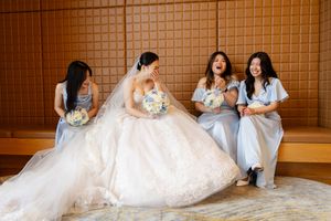 Wedding party seated together on floor in formal attire with matching bouquets.