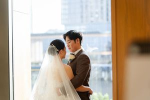 A tender moment between the newlyweds during their first dance in an elegant ballroom with city views.