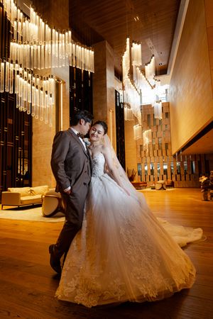 A romantic wedding photoshoot in an elegant venue with dramatic lighting and a flowing white ballgown dress.
