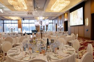 Elegant wedding reception venue with crystal chandeliers and formal table settings in pristine white. Ritz Carlton Wedding