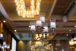 Elegant chandeliers and lighting fixtures illuminate a luxurious wedding venue's ceiling.