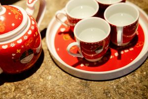 Traditional Chinese tea set featuring a red teapot and matching cups on a serving tray.