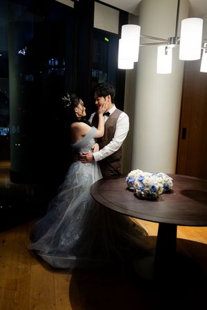 Wedding couple dancing in a dimly lit modern space with pendant lights creating dramatic shadows.