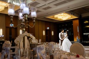 Wedding reception venue with elegant chandeliers and white-draped tables set for celebration.