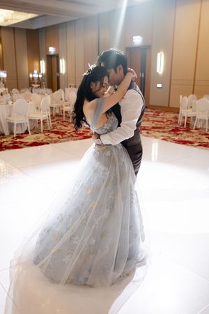 A romantic moment between newlyweds dancing in an elegant ballroom with carpeted floor.