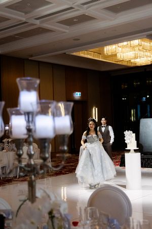 Wedding reception venue with elegant table settings, white linens, and crystal chandeliers.