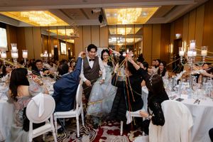 Wedding reception hall with elegant table settings and chandeliers as guests celebrate.