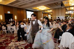 Wedding celebration in a luxurious ballroom with couple in elegant dress and suit surrounded by guests.