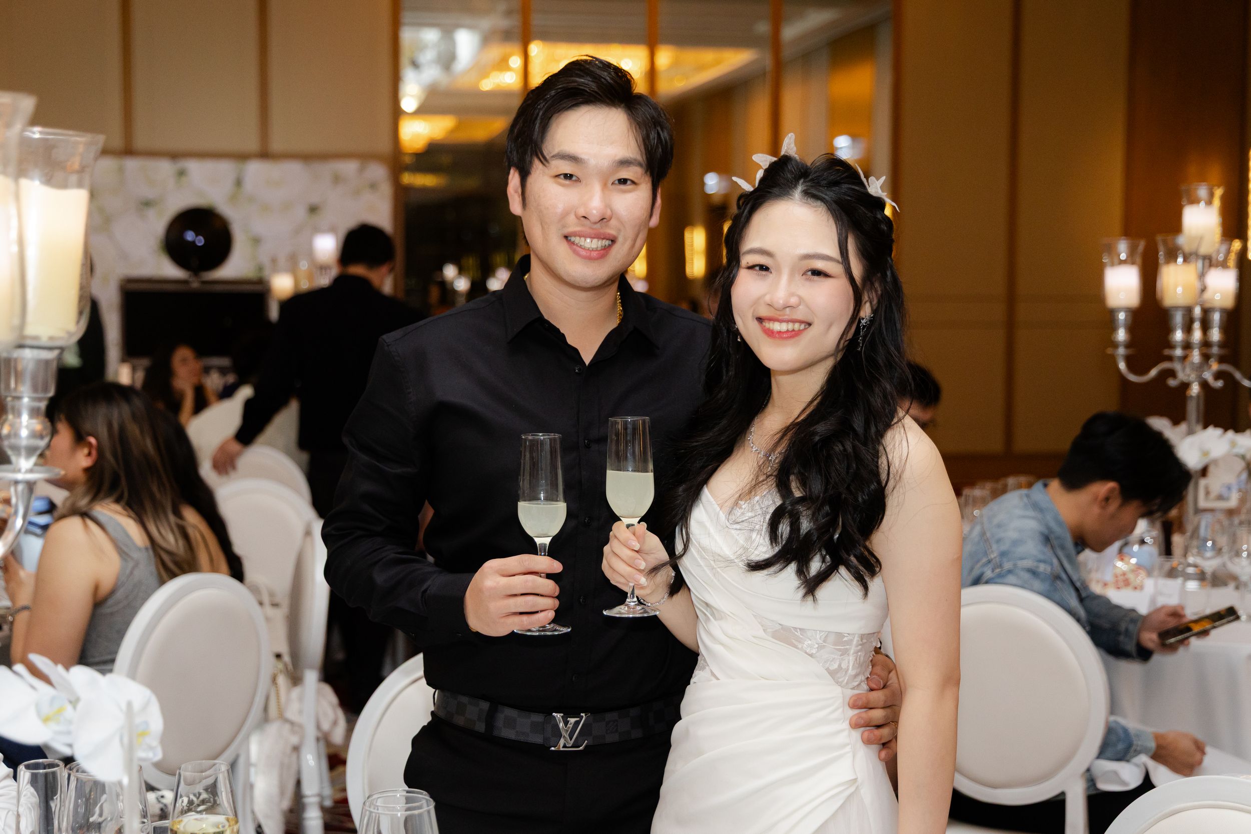 Wedding celebration showing guests raising glasses in a toast at an elegant reception hall.