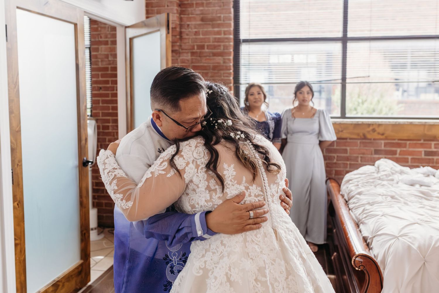 A Catholic bride embraces her father wearing traditional Philipinno wedding attire while the photographer gets pictures of their first look.