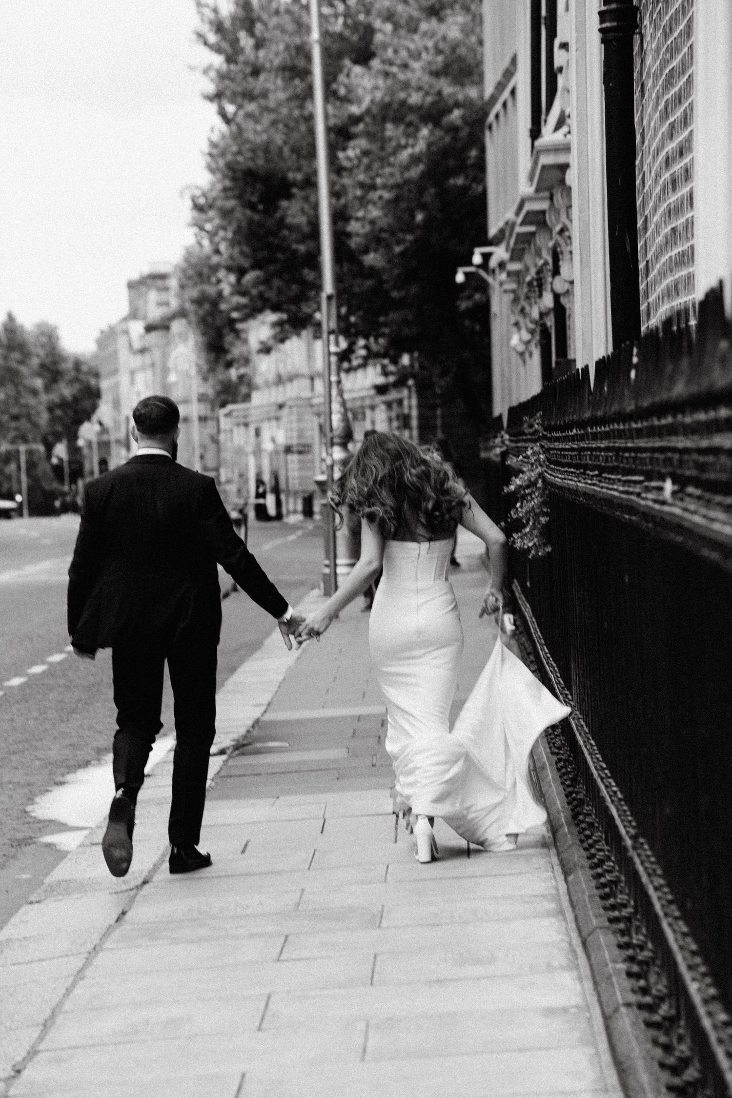 A couple in wedding attire walking along a scenic sidewalk shown in multiple black and white frames.