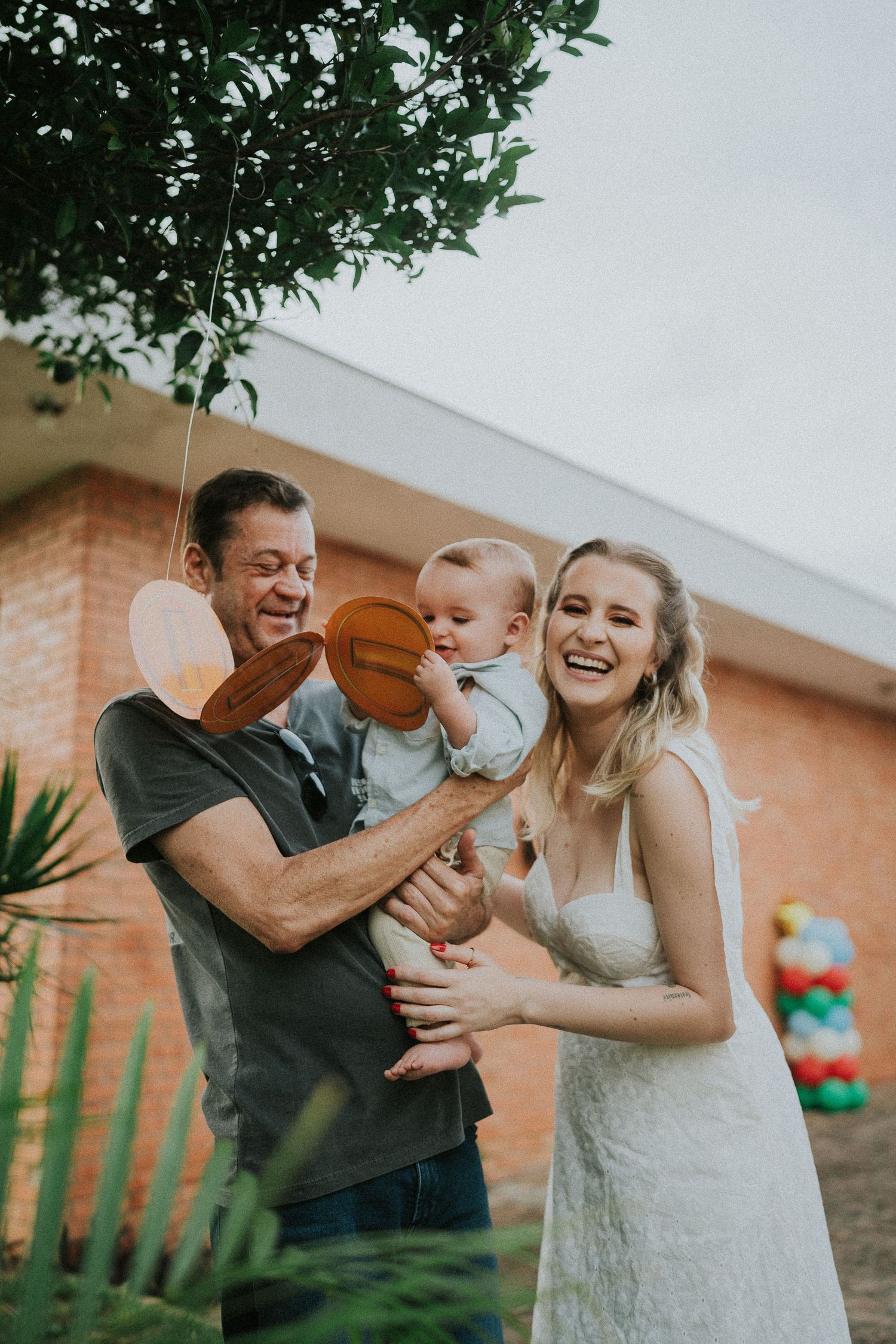 Playful outdoor moment with laughing people sharing cute interaction with baby holding basketball.