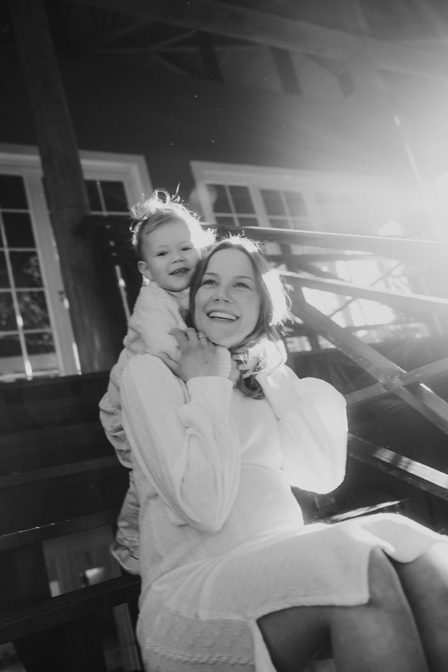 Black and white portrait capturing joyful interaction between caregiver and small child outdoors.