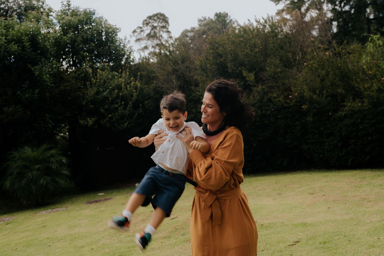 Playful outdoor moment between parent and child in grassy field.