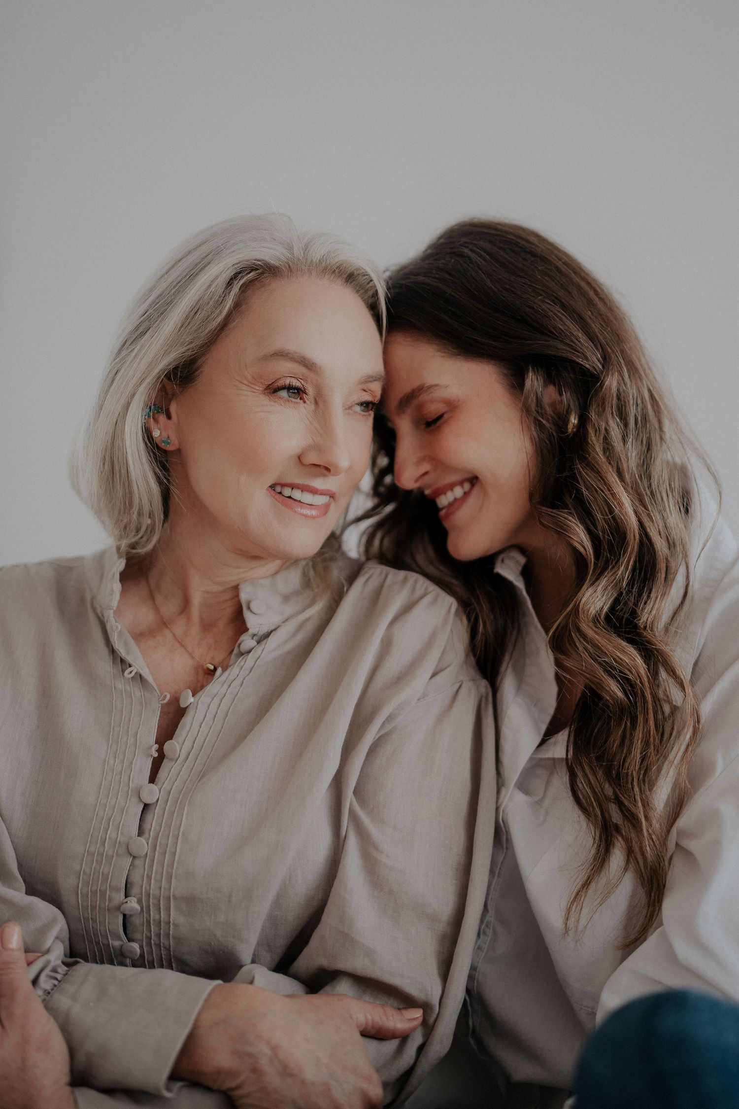 Two generations sharing intimate laughing moment in soft natural light.