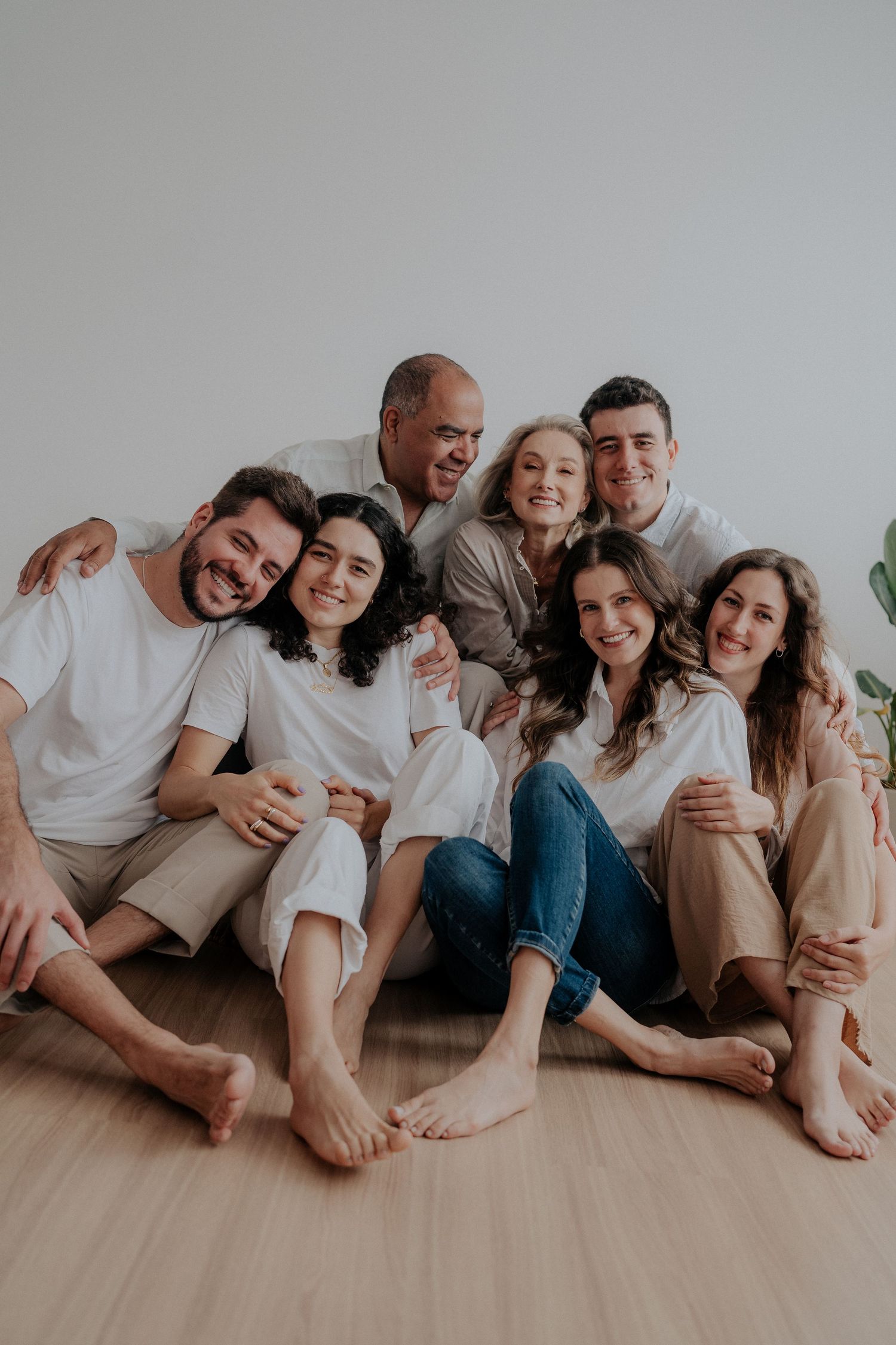 Casual family portrait of group lounging together on floor in neutral clothes.