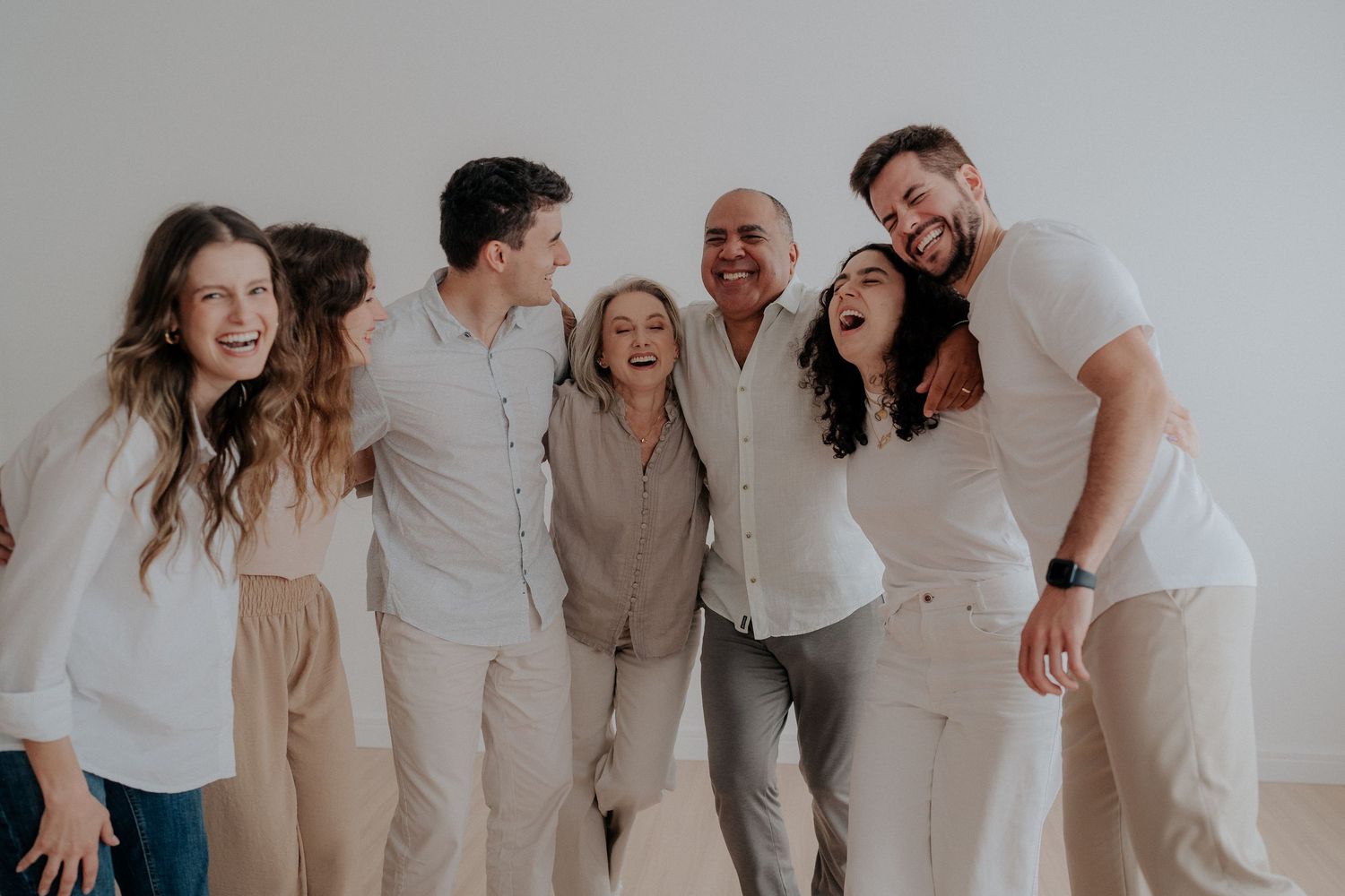 Candid group shot of family laughing together against light background.