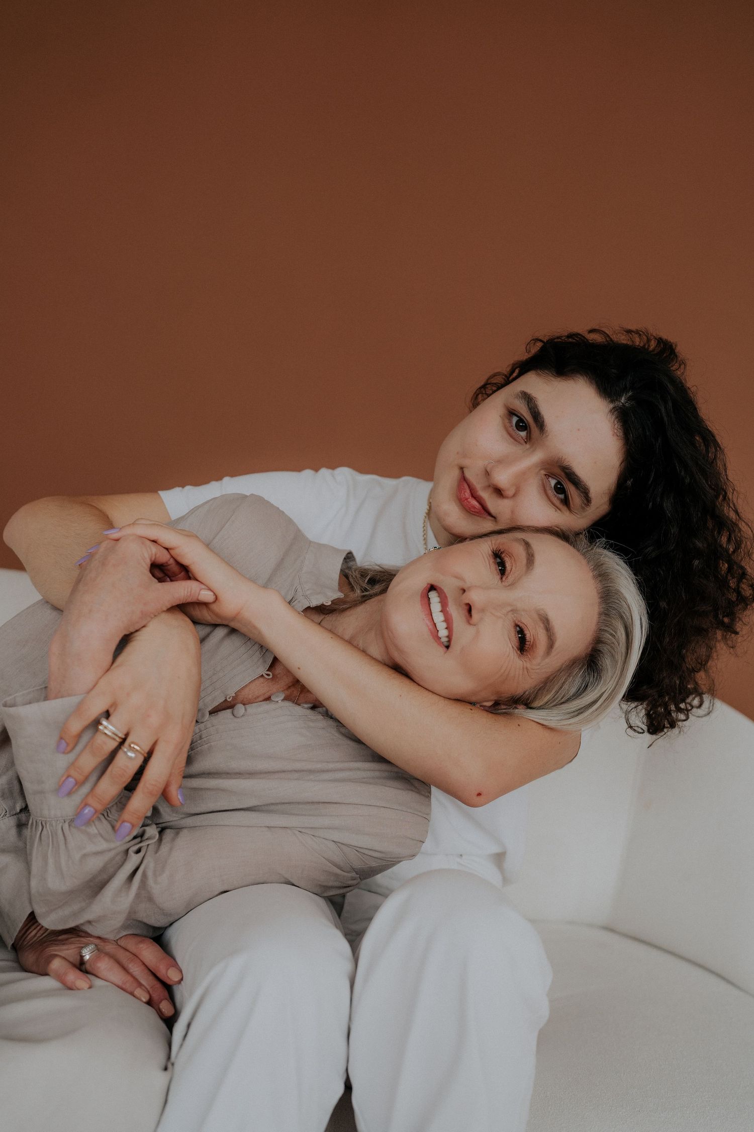 Intimate lifestyle photoshoot of couple lying down in light colored clothing.