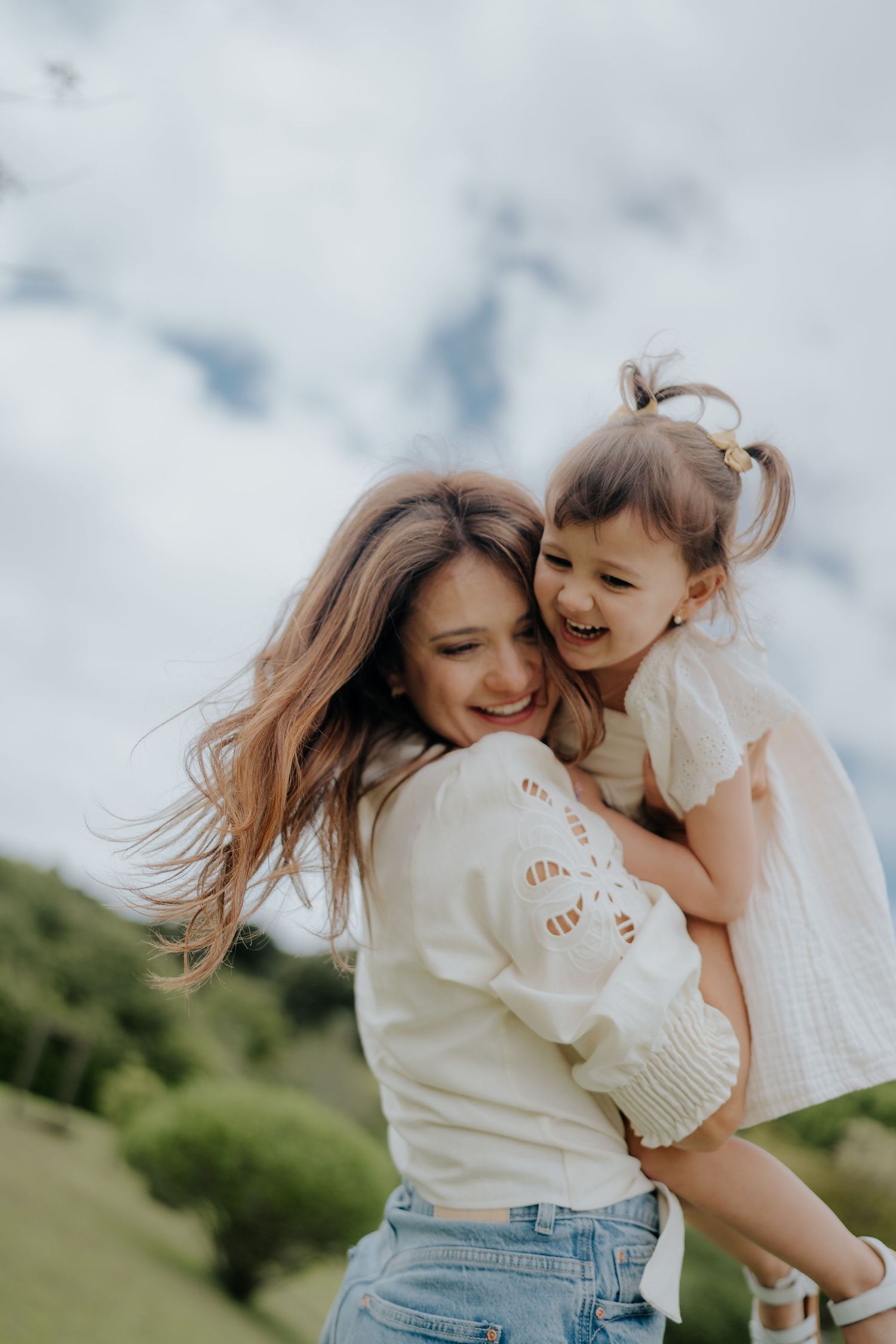 Sweet outdoor portrait against cloudy sky with wind-blown hair.