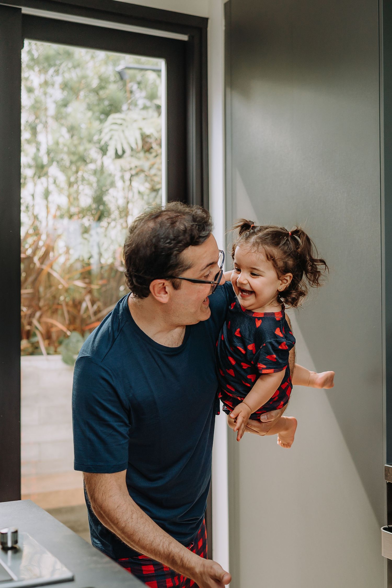 A candid moment of joy and laughter shared between parent and child by a window.