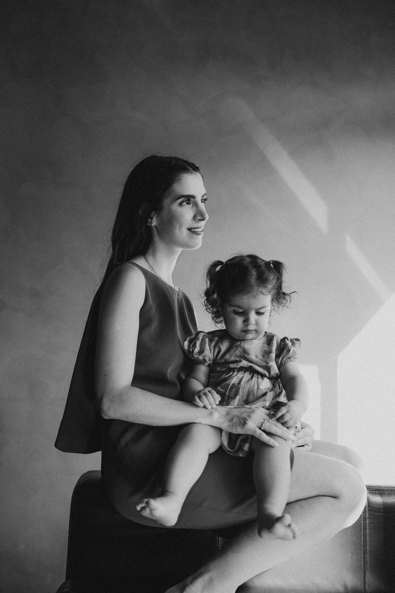 A tender black and white portrait of a parent and child in an elegant setting.