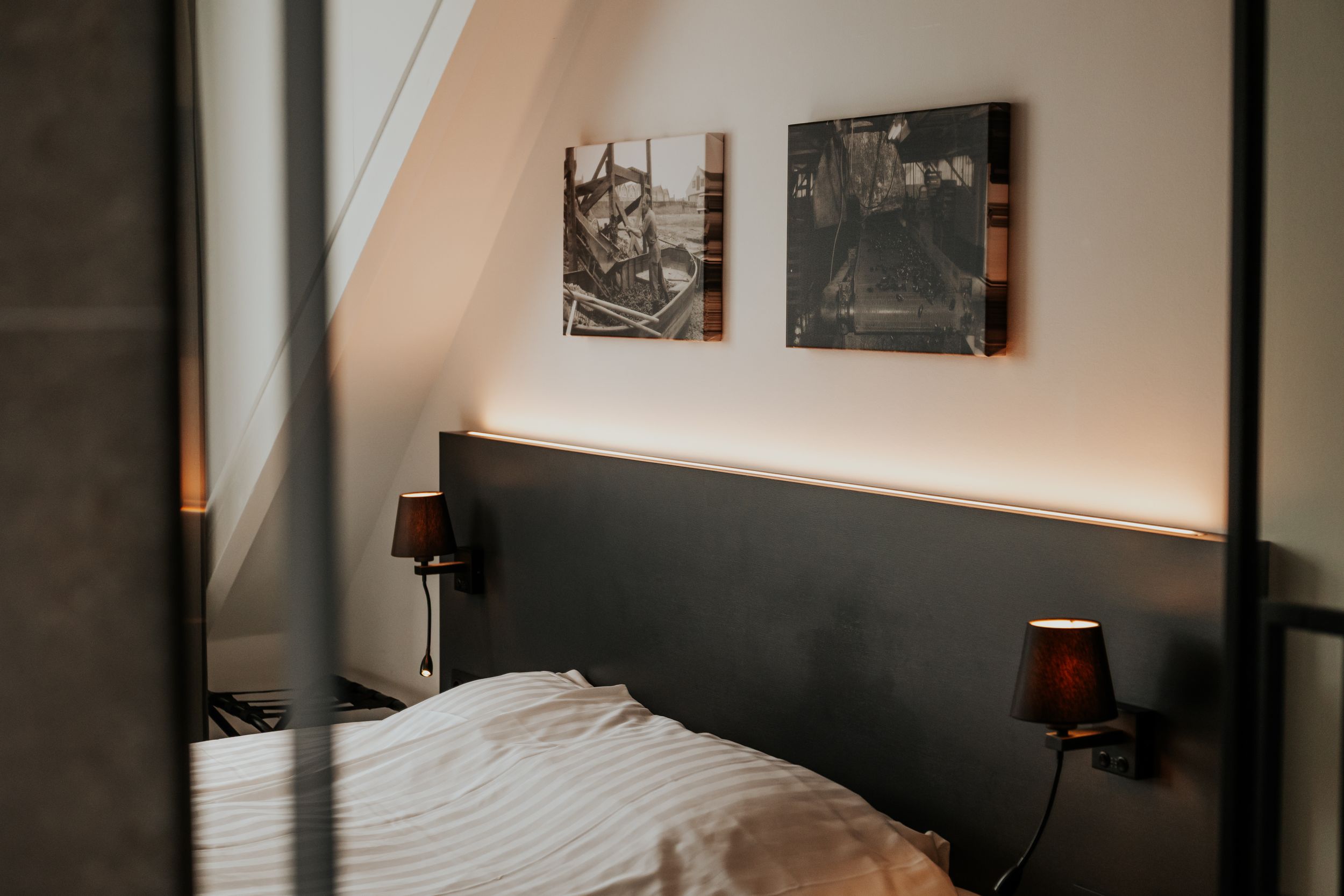Cozy bedroom with warm lighting and artistic wall decor in neutral tones.