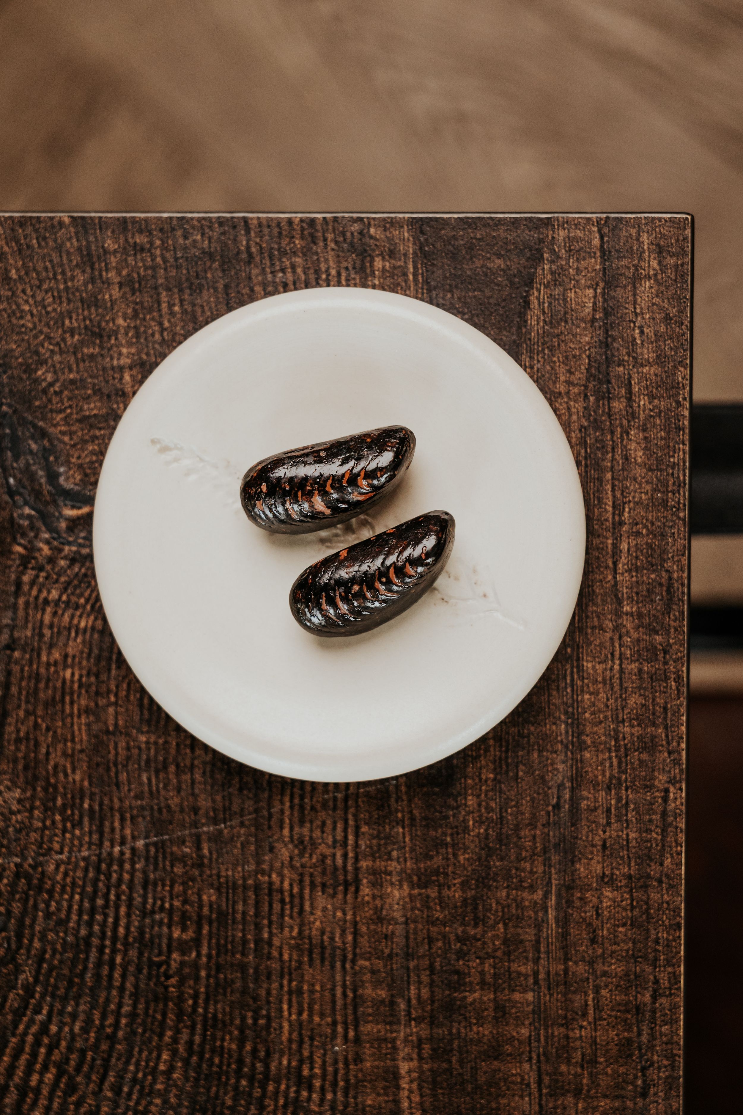 Decorative chocolate pieces displayed on white plate against rustic wooden surface.