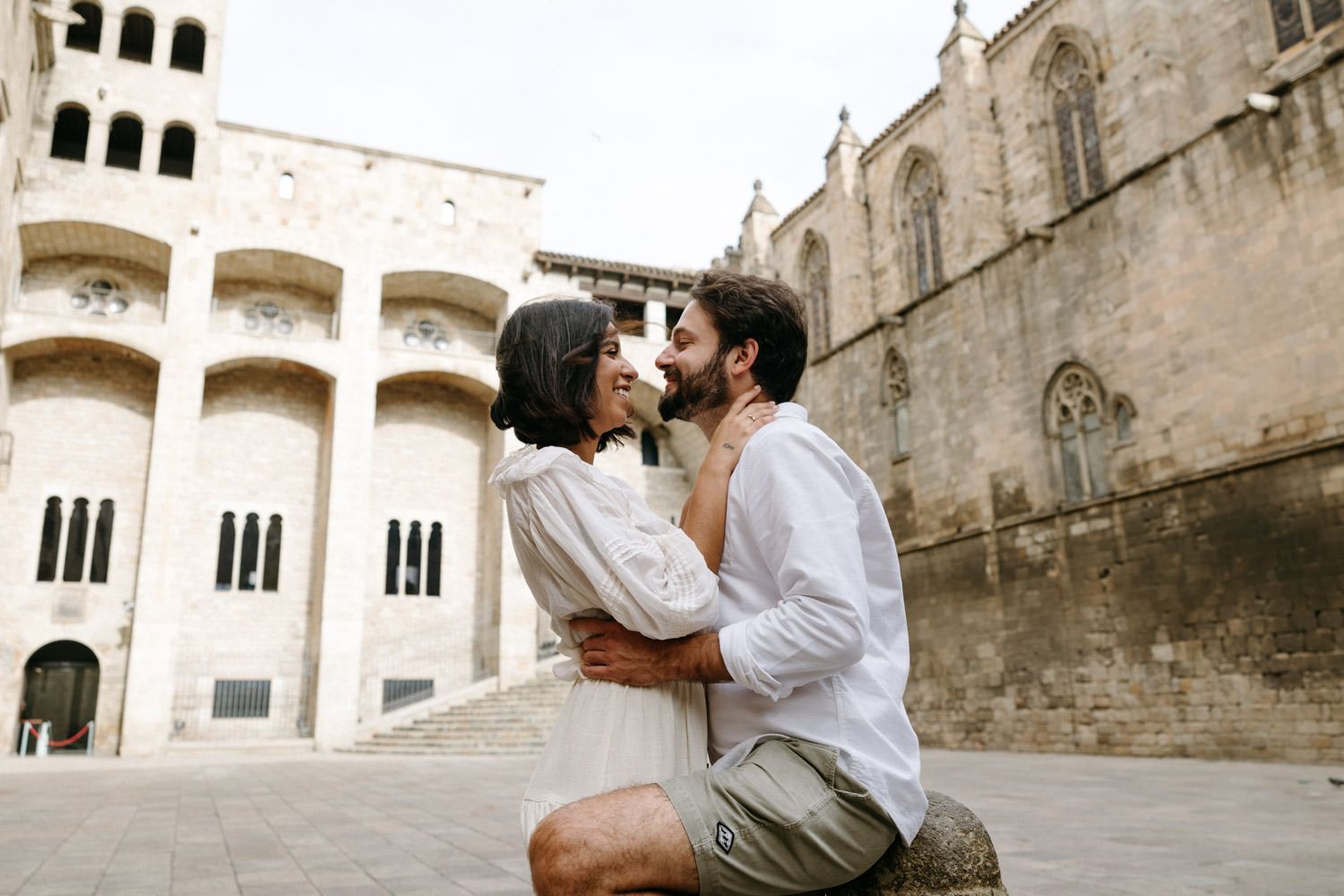 A romantic photoshoot featuring a couple against historic architecture and stone walls.