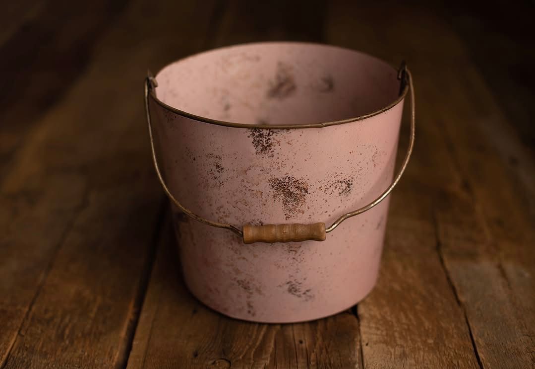 A light pink metal bowl shown in various angles on a rustic wooden surface with natural lighting.