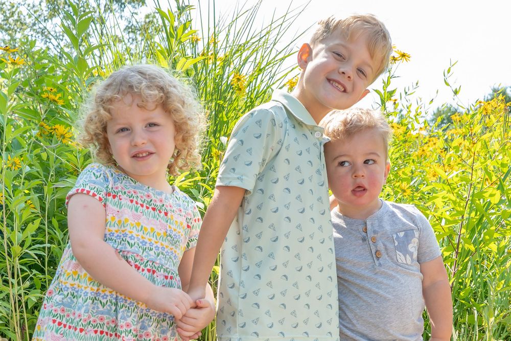Playful children enjoying a sunny day in a field of blooming yellow wildflowers.