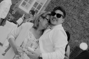 Two wedding guests share a joyful moment together in black and white photography.
