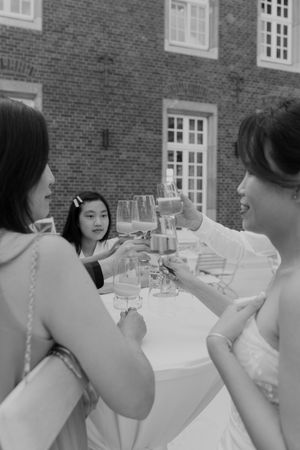 Wedding guests raise glasses for a celebratory toast at an outdoor reception.
