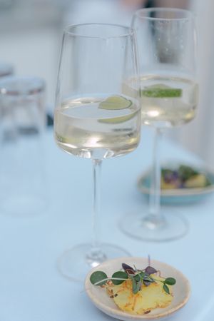 Elegant wine glasses with lime garnish and appetizer plates on a white tablecloth.