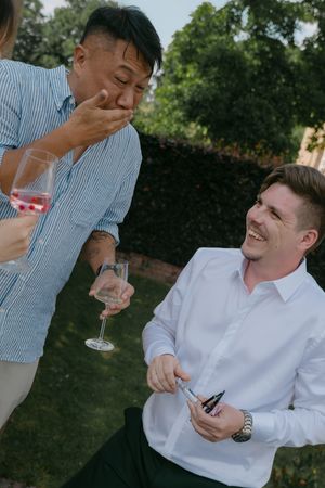 Wedding guests enjoy champagne and laughter during outdoor celebration.