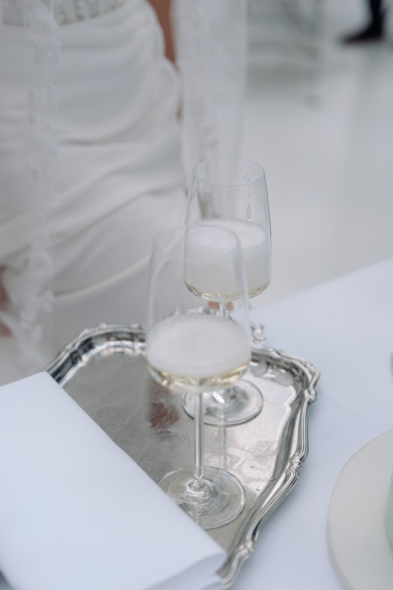 Elegant wine glasses arranged on silver tray at wedding reception.